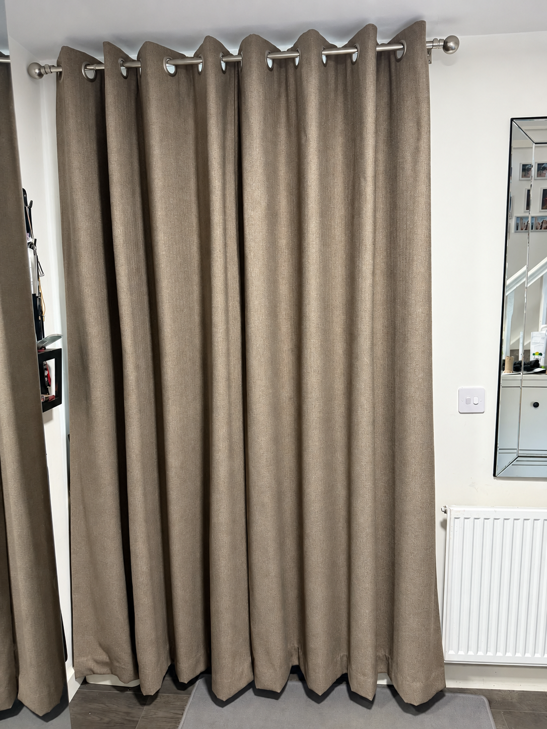Grey eyelet curtains fitted on a chrome curtain pole