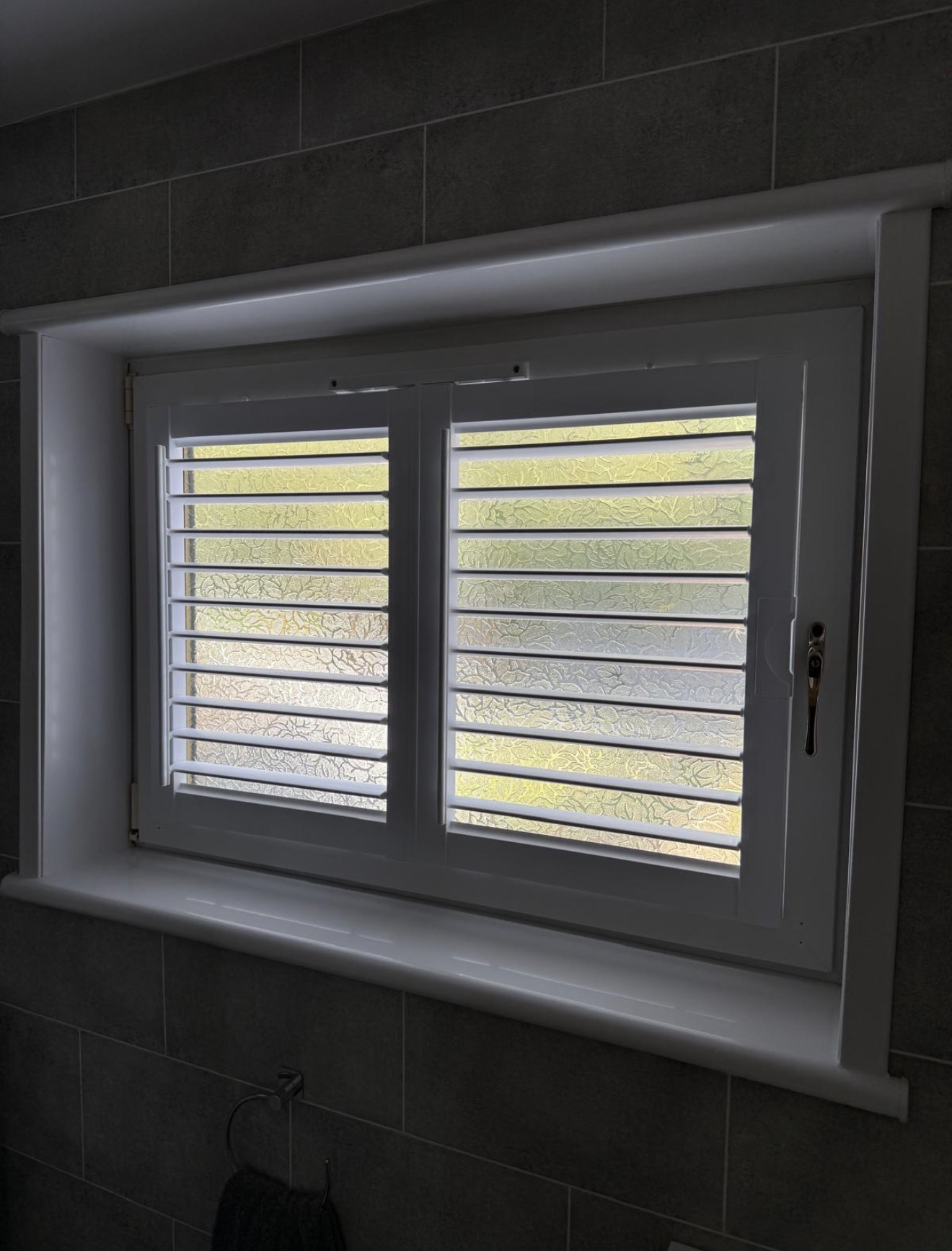 White plantation shutters fitted to a frosted bathroom window