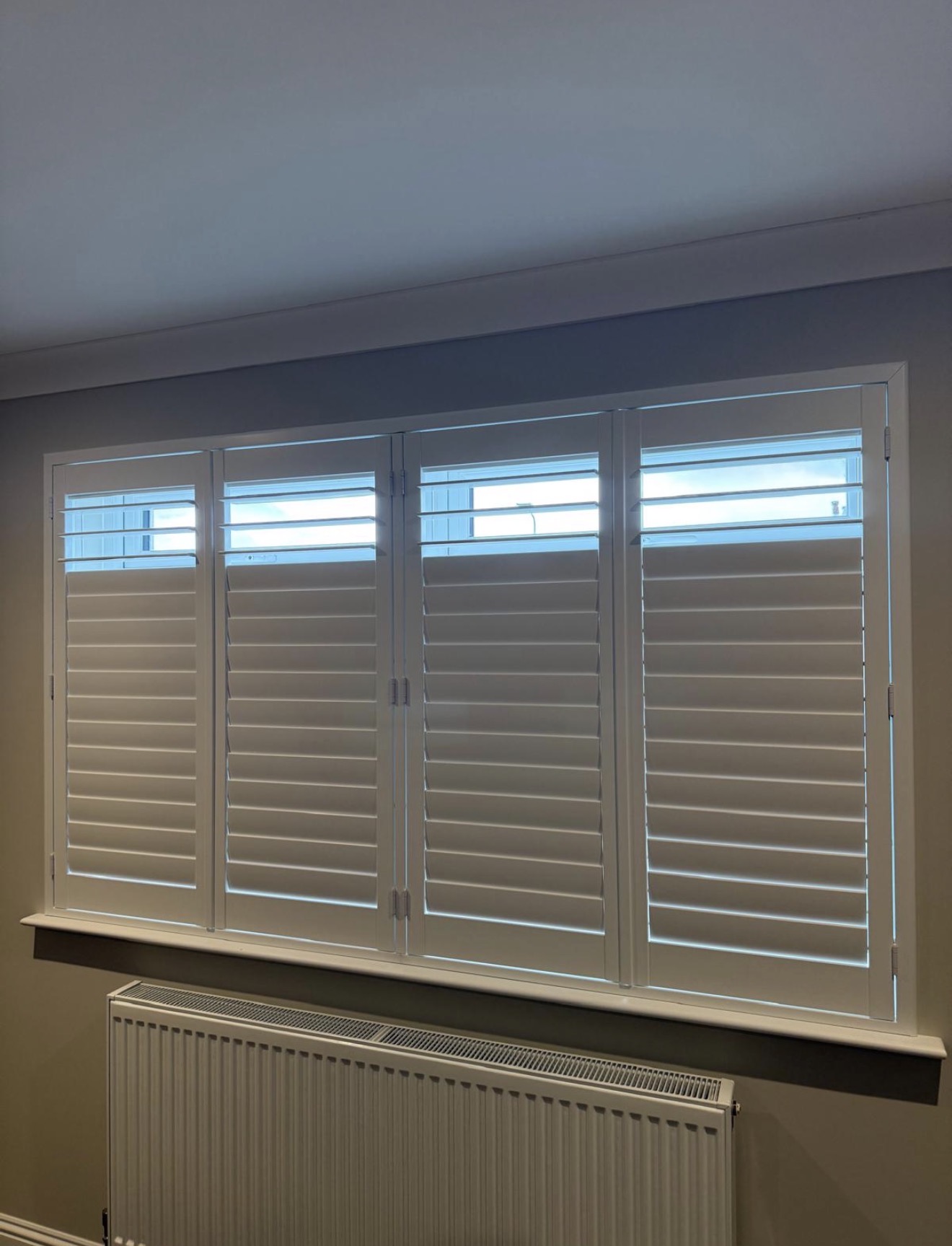 White plantation shutters fitted across a wide window